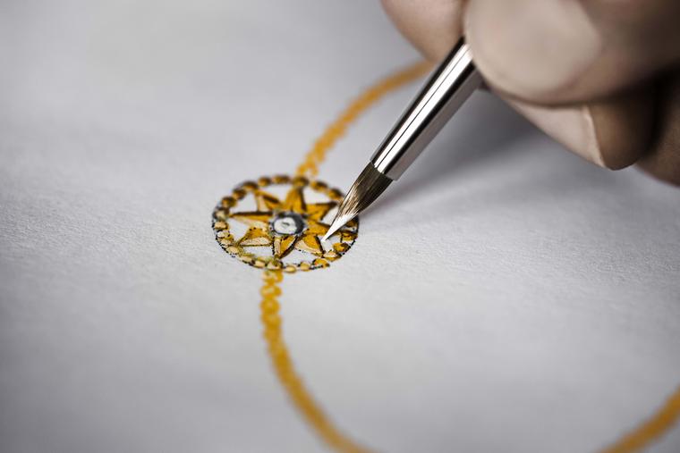 An artist adds fine detail to a gouache of the Rose des Vents bracelet, with its distinctive star motif.
